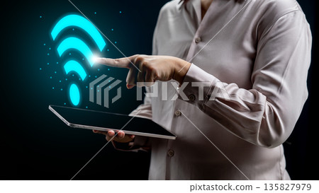 Person holding a tablet and pointing to a glowing blue Wi-Fi symbol representing high-speed internet, wireless connectivity, and digital technology networking Person holding a tablet and pointing to a glowing blue Wi-Fi symbol representing high-speed internet, wireless connectivity, and digital technology networking 135827979