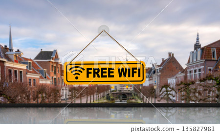 Yellow sign with Free Wifi text hanging on a window. Blurred historic city background with old houses and cloudy sky. Concept of internet connectivity, travel, and hospitality services Yellow sign with Free Wifi text hanging on a window. Blurred historic city background with old houses and cloudy sky. Concept of internet connectivity, travel, and hospitality services 135827981