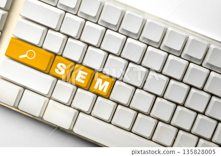 White computer keyboard featuring orange keys spelling out SEM with a search icon, illustrating digital marketing and search engine marketing strategies 135828005
