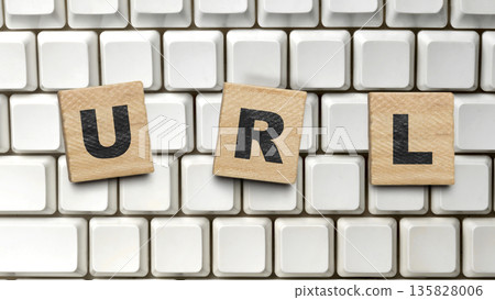 The word URL spelled out using wooden alphabet tiles resting on a vintage white computer keyboard, representing web addresses, internet navigation, and digital technology 135828006