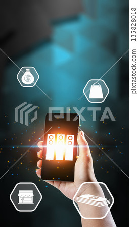 Hand holding a smartphone with glowing server icons and floating digital symbols for shopping, money, and retail business on a dark abstract background 135828018