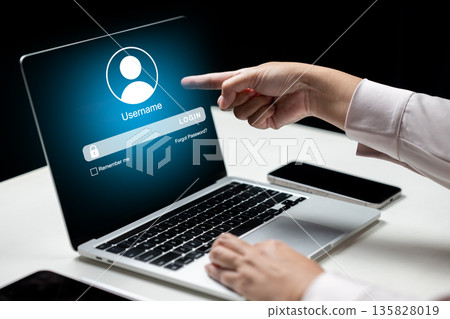 Close-up of a hand pointing at a login screen on a laptop. Concept of cybersecurity, user authentication, data privacy, and secure account access for business or personal use 135828019