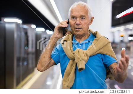 Old man with smartphone in subway station Old man with smartphone in subway station 135828254