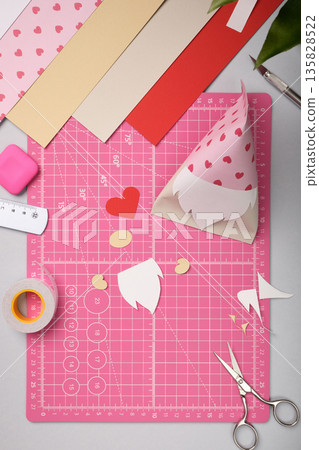 Making a gnome in love craft. All cut-out pieces are lying on pink cutting mat. 135828522