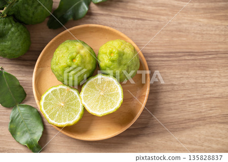Kaffir lime fruit with leaf on wooden background, Thai food ingredient, Table top view Kaffir lime fruit with leaf on wooden background, Thai food ingredient, Table top view 135828837