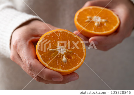 Half Mandarin tangerine orange fruit holding by woman hand Half Mandarin tangerine orange fruit holding by woman hand 135828846