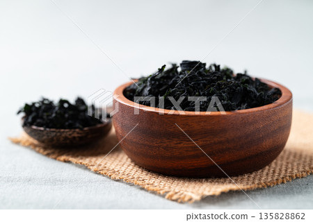 Dried wakame seaweed in a wooden bowl and spoon, Healthy Asian food ingredient Dried wakame seaweed in a wooden bowl and spoon, Healthy Asian food ingredient 135828862