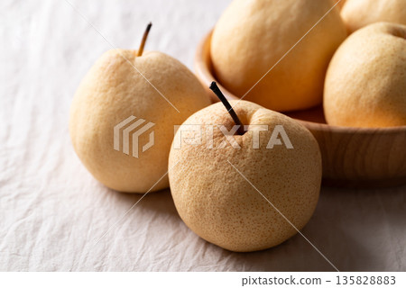 Fresh Asian pears on white wrinkled fabric with soft natural light 135828883