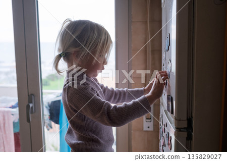 4-Year-Old Child Arranging Colorful Fridge Magnets. 4-Year-Old Child Arranging Colorful Fridge Magnets. 135829027