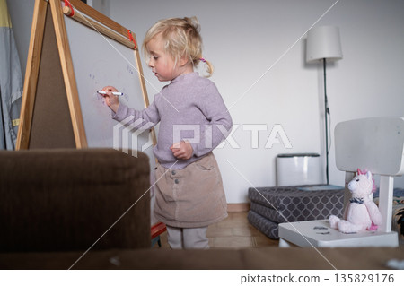 Cute four year old blonde girl playing teacher and teaching numbers to her stuffed toy. 135829176