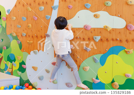 Boy playing bouldering Boy playing bouldering 135829186
