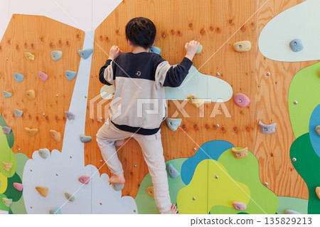 Boy playing bouldering Boy playing bouldering 135829213