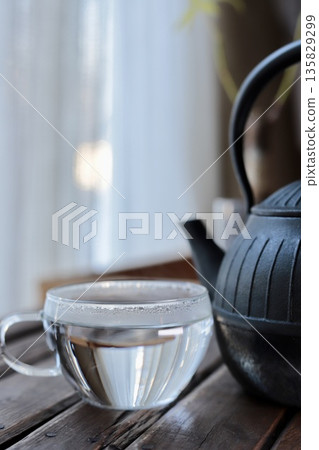 Hot water boiled in an iron kettle and poured into a glass cup for first thing in the morning Hot water boiled in an iron kettle and poured into a glass cup for first thing in the morning 135829299