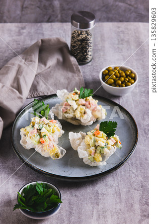 Olivier salad in rice paper bowls on a plate on the table vertical view Olivier salad in rice paper bowls on a plate on the table vertical view 135829603