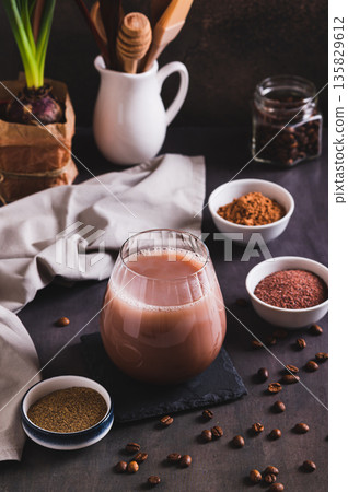 Coffee with spices and cocoa powder in a glass on the table vertical view 135829612