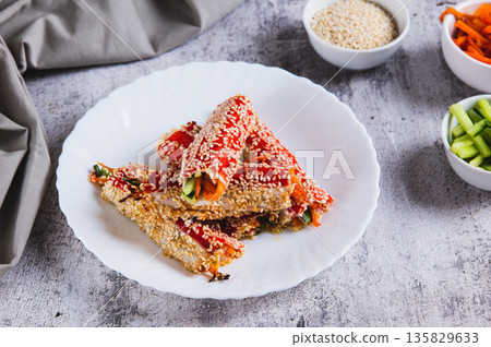 Roasted crab rolls with cucumber and carrots in sesame seeds on a plate on the table 135829633
