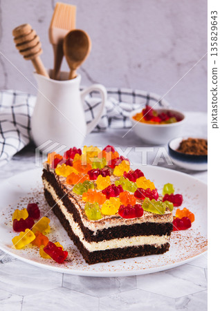 Chocolate cake decorated with gummy bears on a plate on a table vertical view Chocolate cake decorated with gummy bears on a plate on a table vertical view 135829643