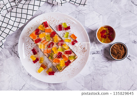 Chocolate cake decorated with gummy bears on a plate on a table top view Chocolate cake decorated with gummy bears on a plate on a table top view 135829645