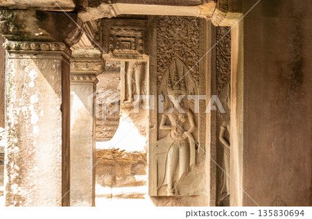 View through stone columns of beautiful Apsara dancer bas-relief carving on wall at ancient Angkor Wat temple in Cambodia View through stone columns of beautiful Apsara dancer bas-relief carving on wall at ancient Angkor Wat temple in Cambodia 135830694