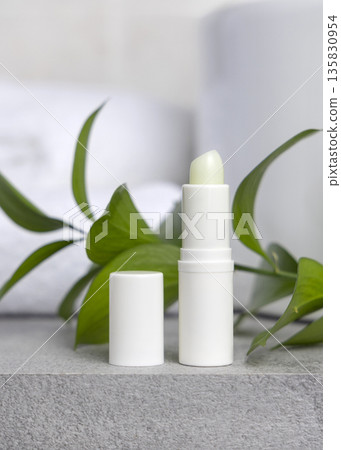 White blank cream tube against green leaves on grey stone in white bathroom, mockup White blank cream tube against green leaves on grey stone in white bathroom, mockup 135830954