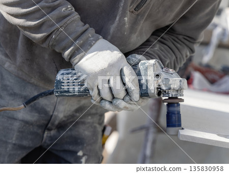 Man drilling holes in ceramic tile with using an angle grinder. Craftmen at work, hands closeup 135830958