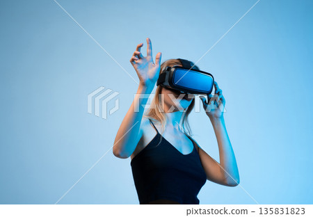 Woman adjusting virtual reality headset and interacting with digital space, immersive VR technology and future innovation 135831823