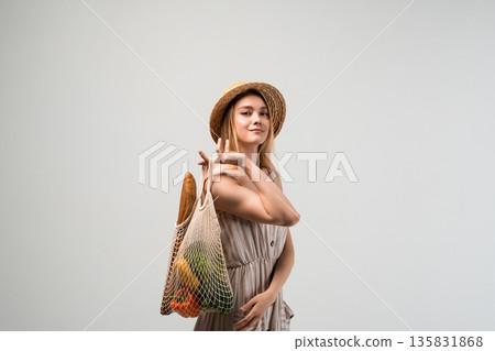 Stylish woman holding reusable grocery bag with bread and vegetables, sustainable shopping, eco friendly lifestyle and conscious living concept Stylish woman holding reusable grocery bag with bread and vegetables, sustainable shopping, eco friendly lifestyle and conscious living concept 135831868