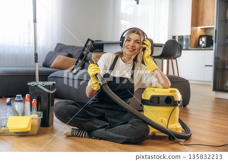 Break time, sitting with vacuum cleaner. Female professional cleaning service worker is domestic room Break time, sitting with vacuum cleaner. Female professional cleaning service worker is domestic room 135832213