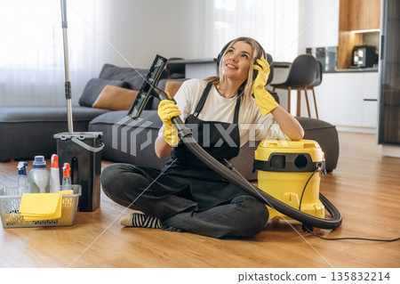 Break time, sitting with vacuum cleaner. Female professional cleaning service worker is domestic room Break time, sitting with vacuum cleaner. Female professional cleaning service worker is domestic room 135832214