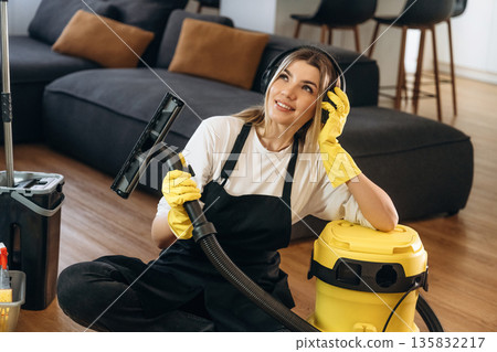 Break time, sitting with vacuum cleaner. Female professional cleaning service worker is domestic room Break time, sitting with vacuum cleaner. Female professional cleaning service worker is domestic room 135832217