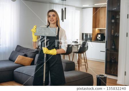 Mop in hands. Female professional cleaning service worker is domestic room 135832240