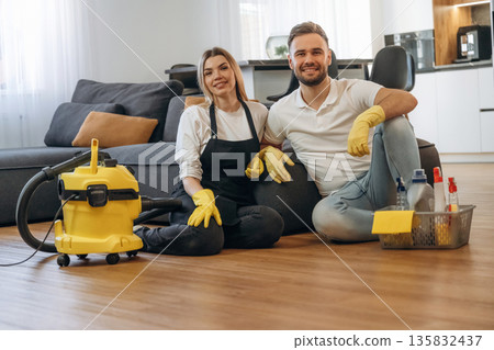 Staff sitting on floor, smiling, rest. Two cleaning service workers are in domestic room 135832437