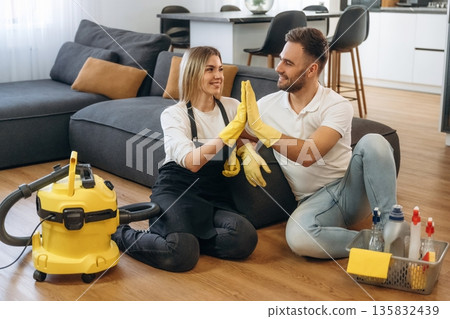 High five gesture. Two cleaning service workers are in domestic room 135832439