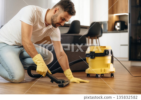Cleaning the parquet. Male professional cleaning service worker is domestic room Cleaning the parquet. Male professional cleaning service worker is domestic room 135832582