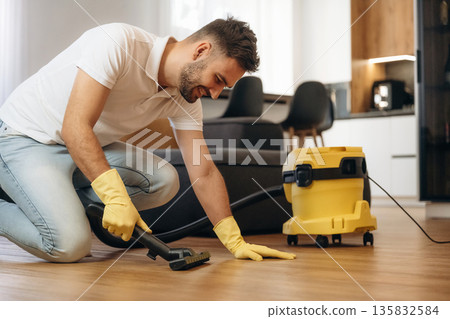 Cleaning the parquet. Male professional cleaning service worker is domestic room Cleaning the parquet. Male professional cleaning service worker is domestic room 135832584