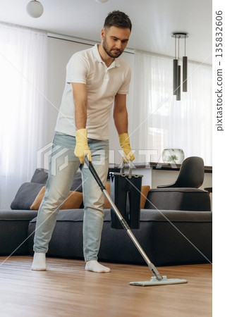 Wet cleaning of the floor. Male professional cleaning service worker is domestic room Wet cleaning of the floor. Male professional cleaning service worker is domestic room 135832606