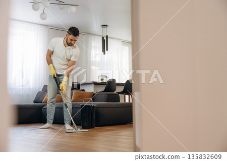 In domestic room. Male professional cleaning service worker In domestic room. Male professional cleaning service worker 135832609