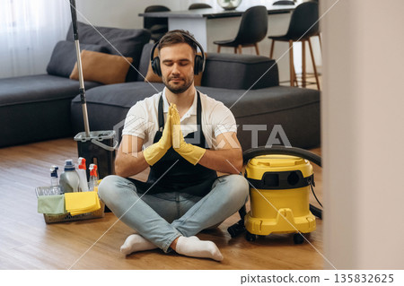 Yoga meditation. lotus pose. Male professional cleaning service worker is domestic room Yoga meditation. lotus pose. Male professional cleaning service worker is domestic room 135832625