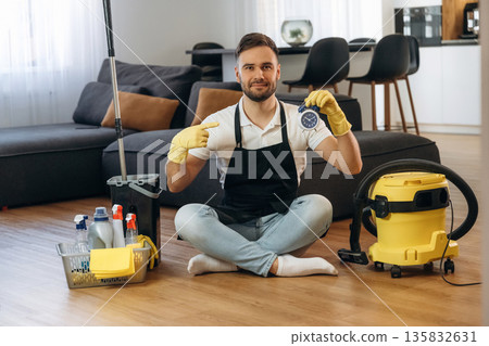 Blue clock in hand. Male professional cleaning service worker is domestic room Blue clock in hand. Male professional cleaning service worker is domestic room 135832631