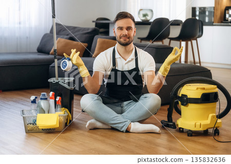 Doing yoga, meditation. Male professional cleaning service worker is domestic room Doing yoga, meditation. Male professional cleaning service worker is domestic room 135832636