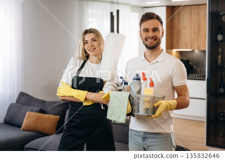 Woman is in uniform, standing. Two cleaning service workers are in domestic room Woman is in uniform, standing. Two cleaning service workers are in domestic room 135832646