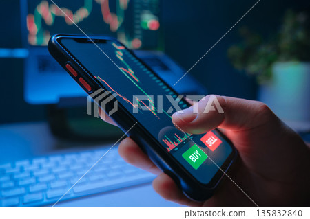 Trader using smartphone investment app to analyze and buying stocks or crypto Trader using smartphone investment app to analyze and buying stocks or crypto 135832840