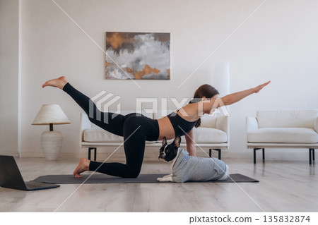 Yoga exercise. Woman with pug dog is at home 135832874
