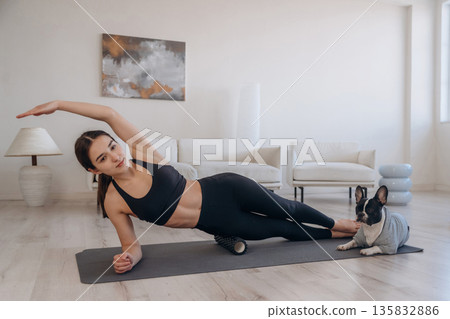Woman with pug dog is doing yoga at home Woman with pug dog is doing yoga at home 135832886