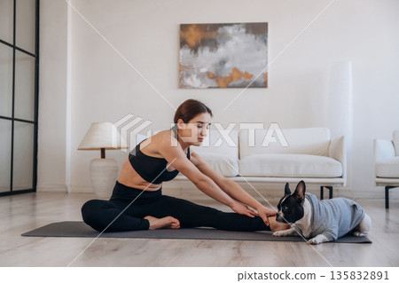 Stretching warm ups. Woman with pug dog is doing yoga at home Stretching warm ups. Woman with pug dog is doing yoga at home 135832891