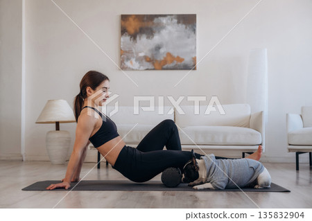 Side view. Woman with pug dog is doing yoga at home 135832904