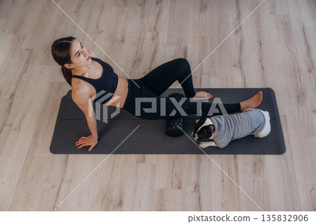 Taking a break. Woman with pug dog is doing yoga at home Taking a break. Woman with pug dog is doing yoga at home 135832906