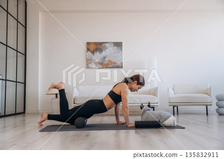 On the black mat, exercise. Woman with pug dog is doing yoga at home On the black mat, exercise. Woman with pug dog is doing yoga at home 135832911