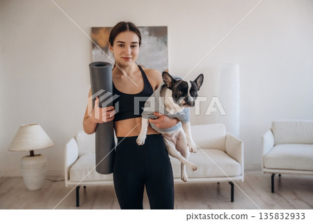 Sportive woman in yoga clothes is with pug dog at home 135832933