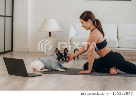 Stroking the dog. Woman with pug is doing yoga at home Stroking the dog. Woman with pug is doing yoga at home 135832947